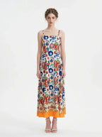 Woman wearing a vibrant printed midi dress with spaghetti straps and a square neckline.