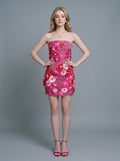 Woman in a strapless pink floral embroidered mini dress, standing with hands on hips