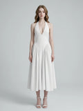 Woman wearing a white halter neck midi dress with a V-neckline and flared skirt.