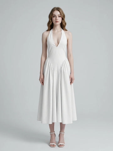Woman wearing a white halter neck midi dress with a V-neckline and flared skirt.