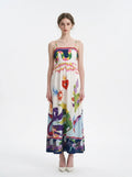 Woman wearing a white midi dress with a colorful graphic print and spaghetti straps from the front