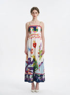 Woman wearing a white midi dress with a colorful graphic print and spaghetti straps from the front