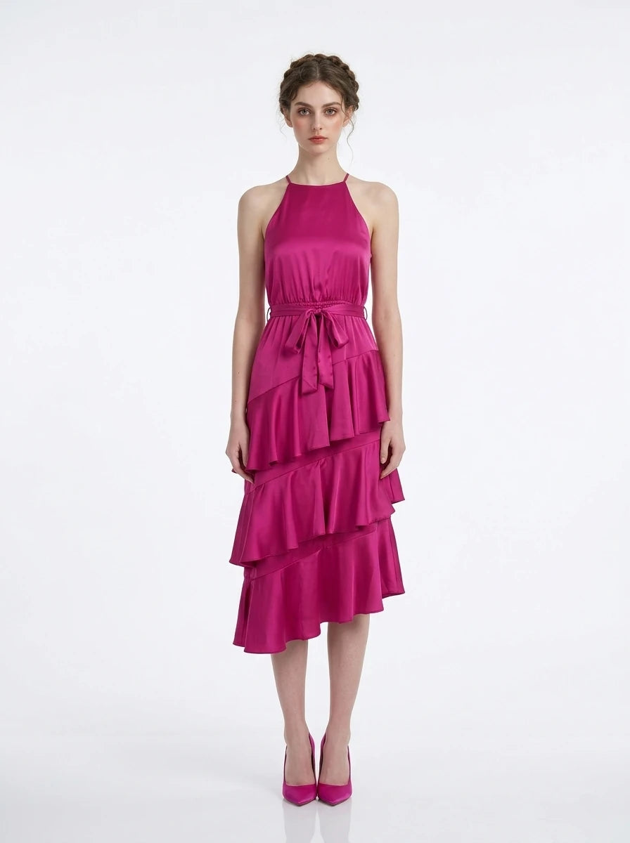 Woman wearing a fuchsia satin halter neck tiered midi dress with a self-tie belt