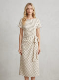 Woman wearing a cream polka dot midi wrap dress with short sleeves