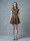 Woman in leopard print fit and flare dress with crew neck and cap sleeves standing against a grey background.
