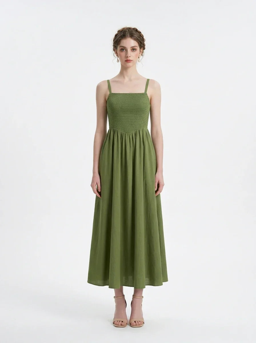 Woman wearing a green linen blend midi dress with a smocked bodice and spaghetti straps, front view.