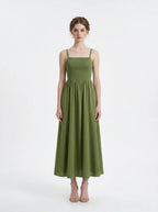 Woman wearing a green linen blend midi dress with a smocked bodice and spaghetti straps, front view.