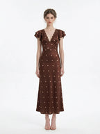 Model wearing a brown polka dot midi dress with a v-neckline and ruffled sleeves.