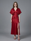 Woman in a red satin V-neck dress with kimono sleeves and a high slit, front view