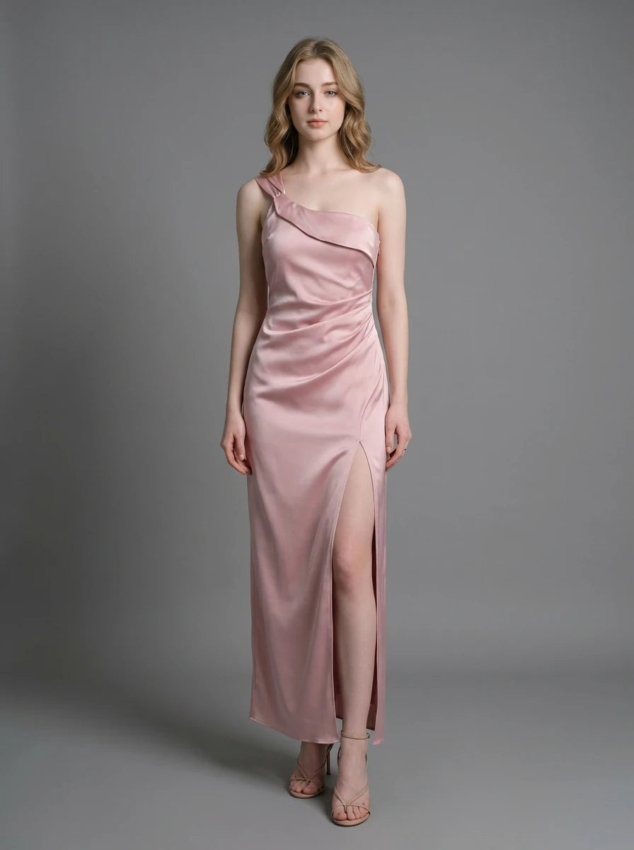 Woman wearing a dusty rose satin one-shoulder maxi dress with a high slit, standing against a grey background.