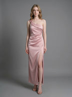 Woman wearing a dusty rose satin one-shoulder maxi dress with a high slit, standing against a grey background.