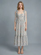 Woman wearing a floral print midi dress with tie shoulder straps and a ruched bodice