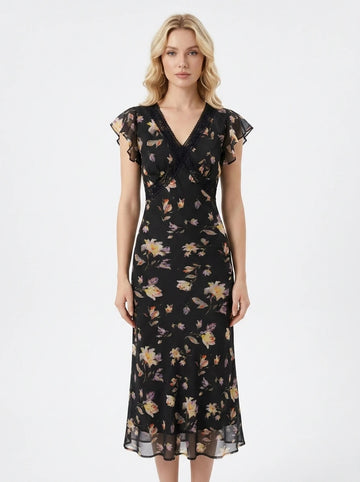 Woman wearing a black floral print midi dress with flutter sleeves and lace trim.