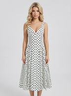 Woman wearing a white sleeveless V-neck dress with black polka dots