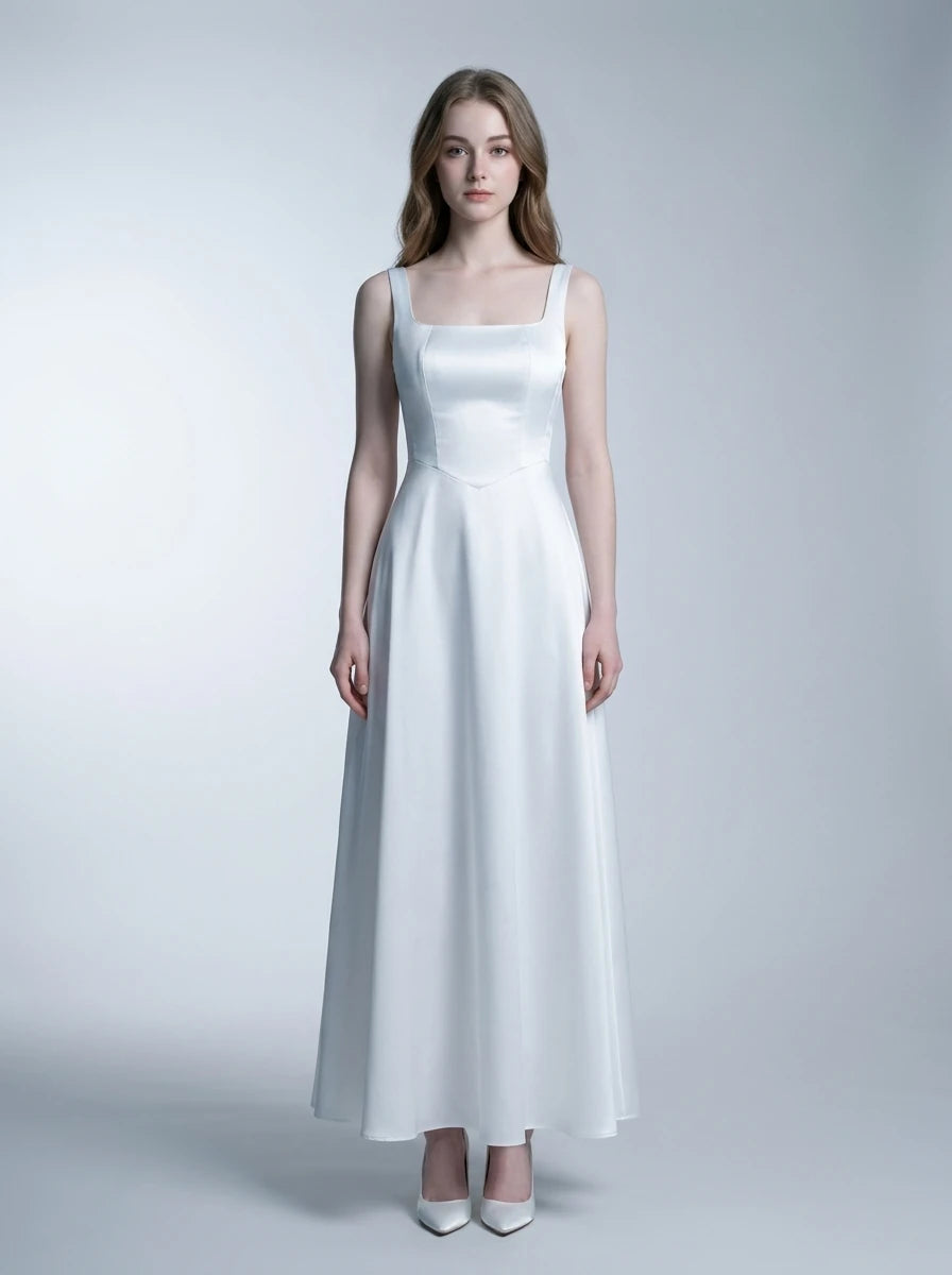 Woman wearing a white satin floor-length dress with a square neckline and tank straps, standing against a white background.