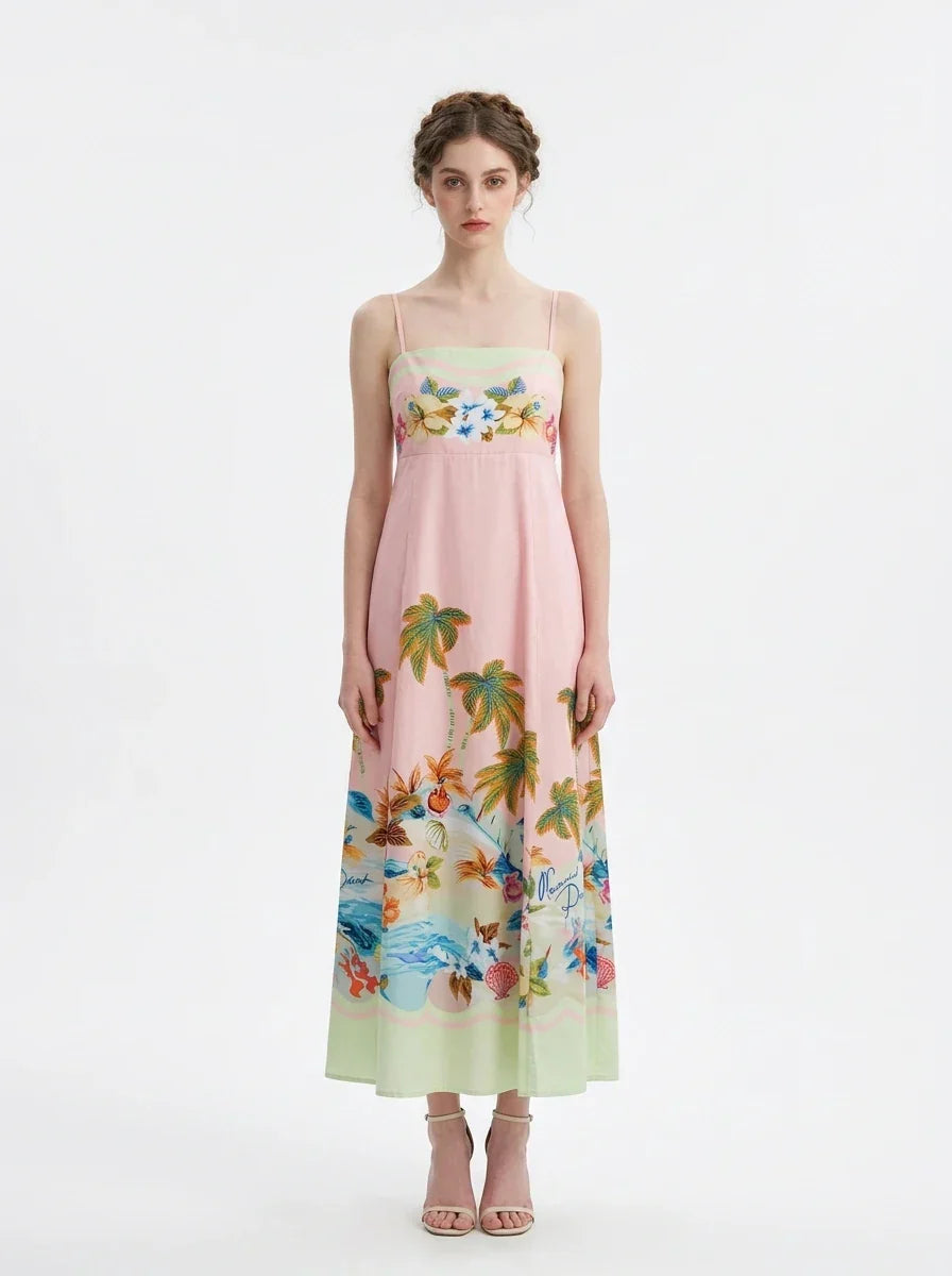 Woman wearing a pink midi dress with spaghetti straps and a tropical print of palm trees and flowers.