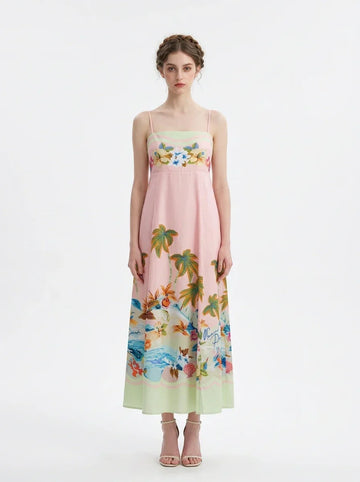 Woman wearing a pink midi dress with spaghetti straps and a tropical print of palm trees and flowers.