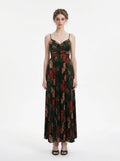 Woman in a dark green floral print maxi dress with spaghetti straps and a pleated skirt, front view