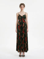 Woman in a dark green floral print maxi dress with spaghetti straps and a pleated skirt, front view