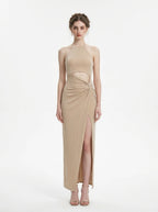Woman wearing a champagne sparkly knit halter neck maxi dress with a cutout waist and thigh-high slit