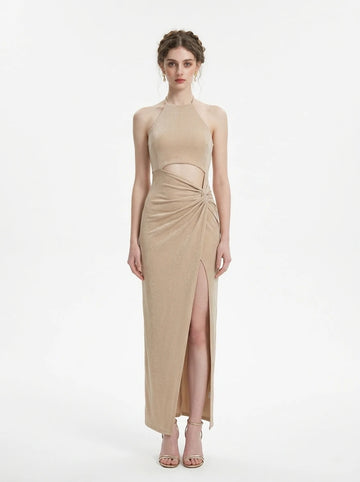 Woman wearing a champagne sparkly knit halter neck maxi dress with a cutout waist and thigh-high slit