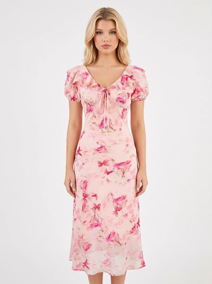 Woman wearing a pink floral print midi dress with a v-neck and tie-front detail.