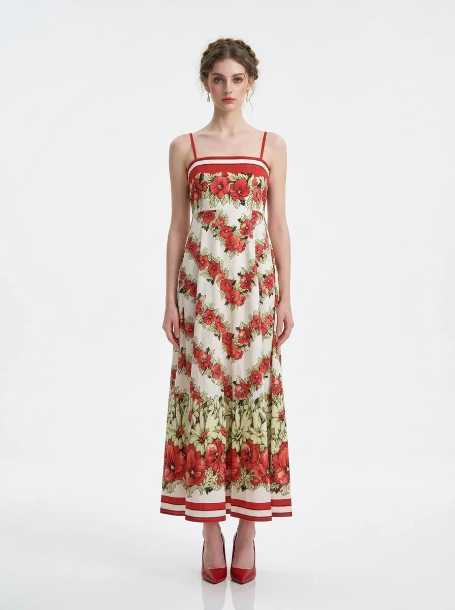 Woman wearing a white maxi dress with a red floral print and red trim, standing against a white background.