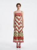 Woman wearing a white maxi dress with a red floral print and red trim, standing against a white background.