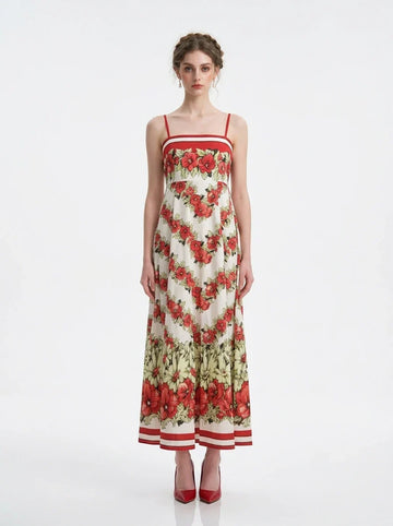 Woman wearing a white maxi dress with a red floral print and red trim, standing against a white background.