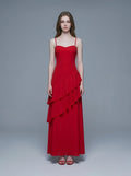 Woman wearing a red, floor-length, spaghetti strap dress with a sweetheart neckline and tiered ruffle detailing on the front