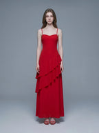 Woman wearing a red, floor-length, spaghetti strap dress with a sweetheart neckline and tiered ruffle detailing on the front