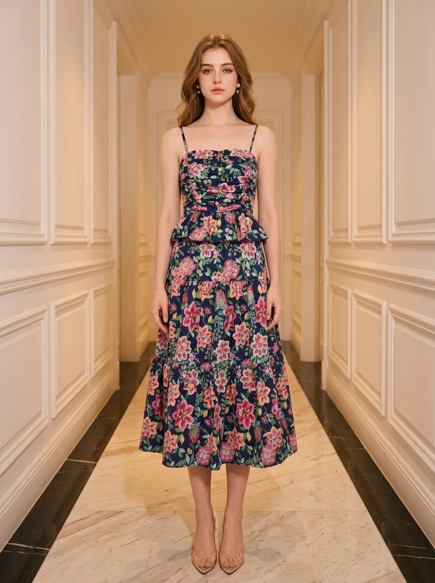 Woman wearing a navy floral print midi dress with spaghetti straps and a peplum waist, standing in a hallway.