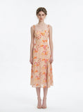 Woman wearing a peach floral print midi dress with sweetheart neckline and tie shoulder straps