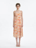Woman wearing a peach floral print midi dress with sweetheart neckline and tie shoulder straps