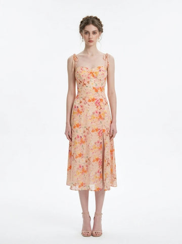 Woman wearing a peach floral print midi dress with sweetheart neckline and tie shoulder straps