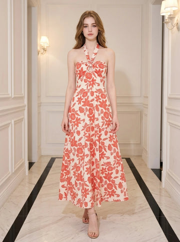 Woman wearing a cream and coral floral print halter neck midi dress