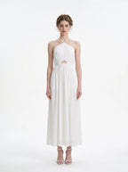 Woman wearing a white halter neck midi dress with a cut-out detail and empire waist