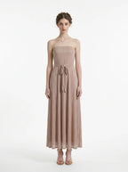 Woman wearing a strapless metallic knit A-line maxi dress with a self-tie belt