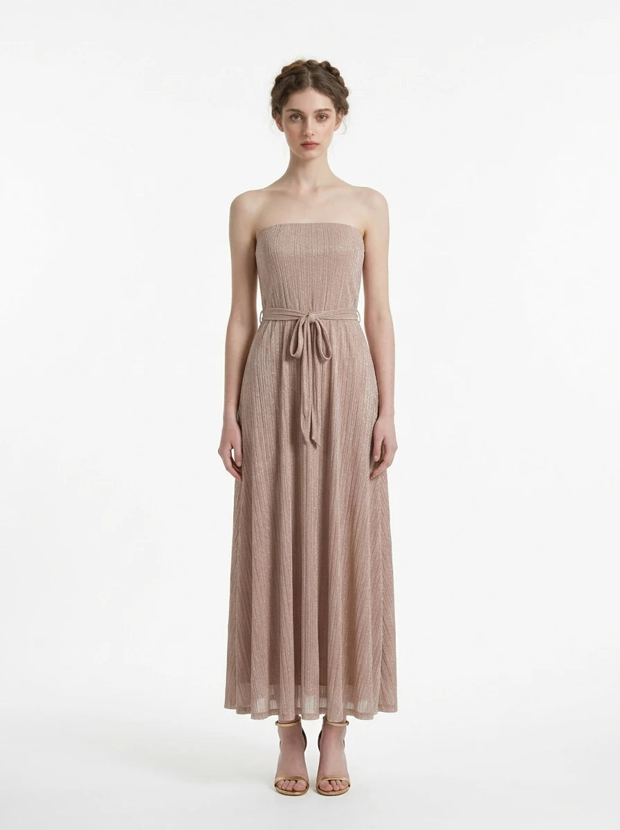 Woman wearing a strapless metallic knit A-line maxi dress with a self-tie belt