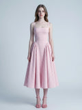 woman wearing a pink gingham midi dress with spaghetti straps and a full pleated skirt