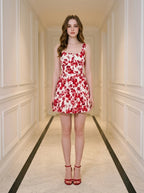 Woman wearing a red and white floral print sleeveless fit and flare dress with a square neckline, standing in a hallway.