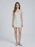 Woman wearing a white floral print mini dress with spaghetti straps and a sweetheart neckline.