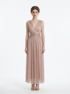 woman in a rose gold metallic a-line maxi dress with a v-neckline and ruched empire waist