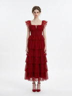Woman wearing a red tiered tulle dress with ruffled cap sleeves and a square neckline