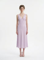 Woman wearing a lilac midi dress with a V-neckline and sleeveless design, standing against a white background.