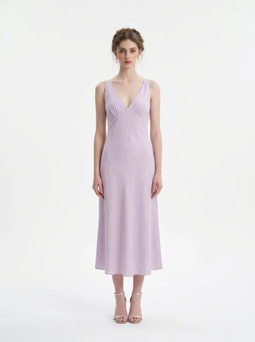 Woman wearing a lilac midi dress with a V-neckline and sleeveless design, standing against a white background.