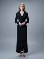 Woman in a black long-sleeved V-neck gown with a front knot and high slit, standing against a grey backdrop.