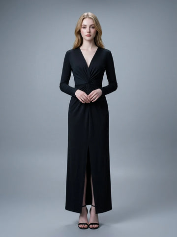Woman in a black long-sleeved V-neck gown with a front knot and high slit, standing against a grey backdrop.