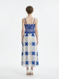 Woman wearing a pink midi dress with a tropical print and spaghetti straps, back view