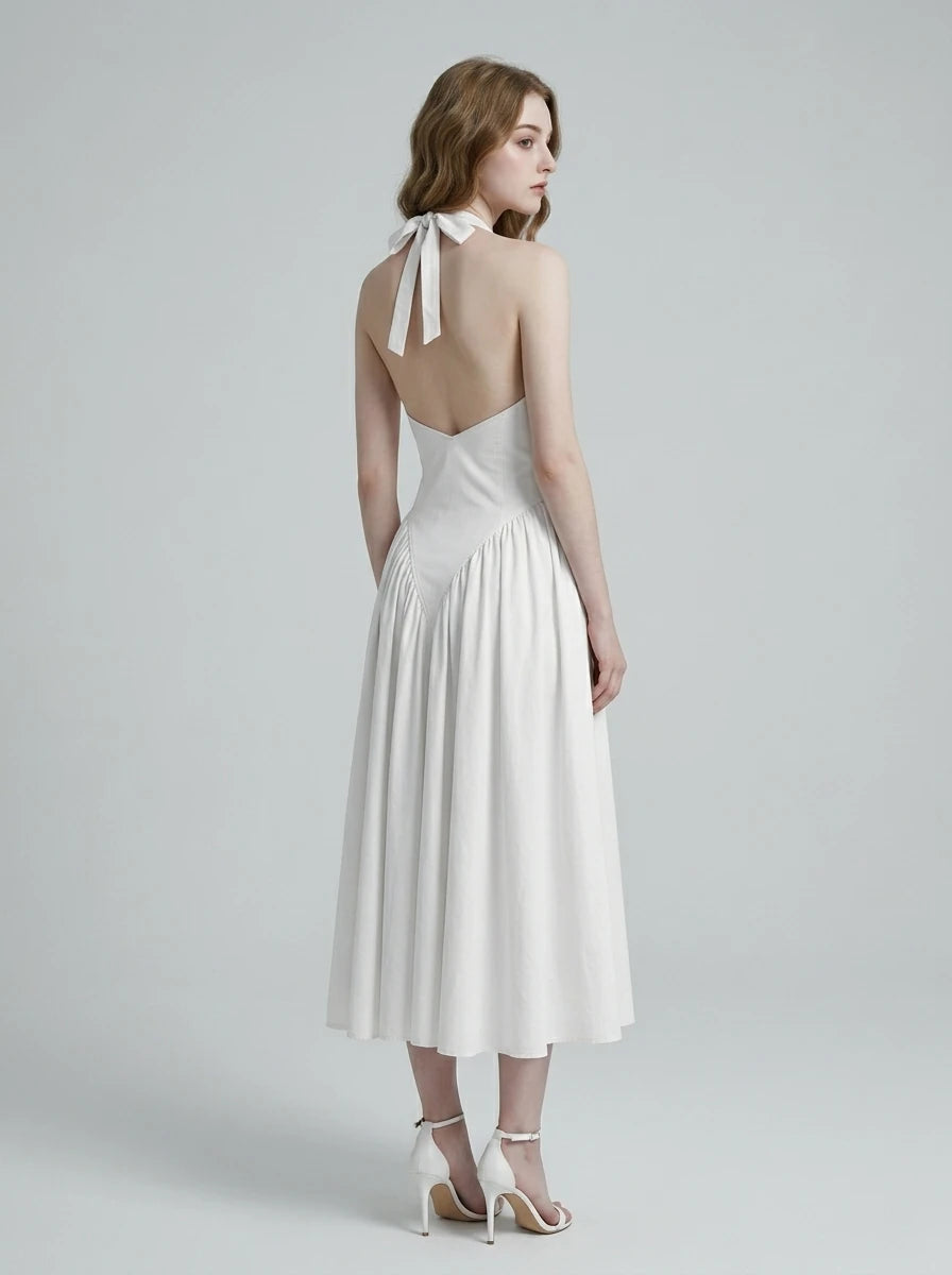 Woman wearing a white halter neck midi dress with a V-neckline and flared skirt.